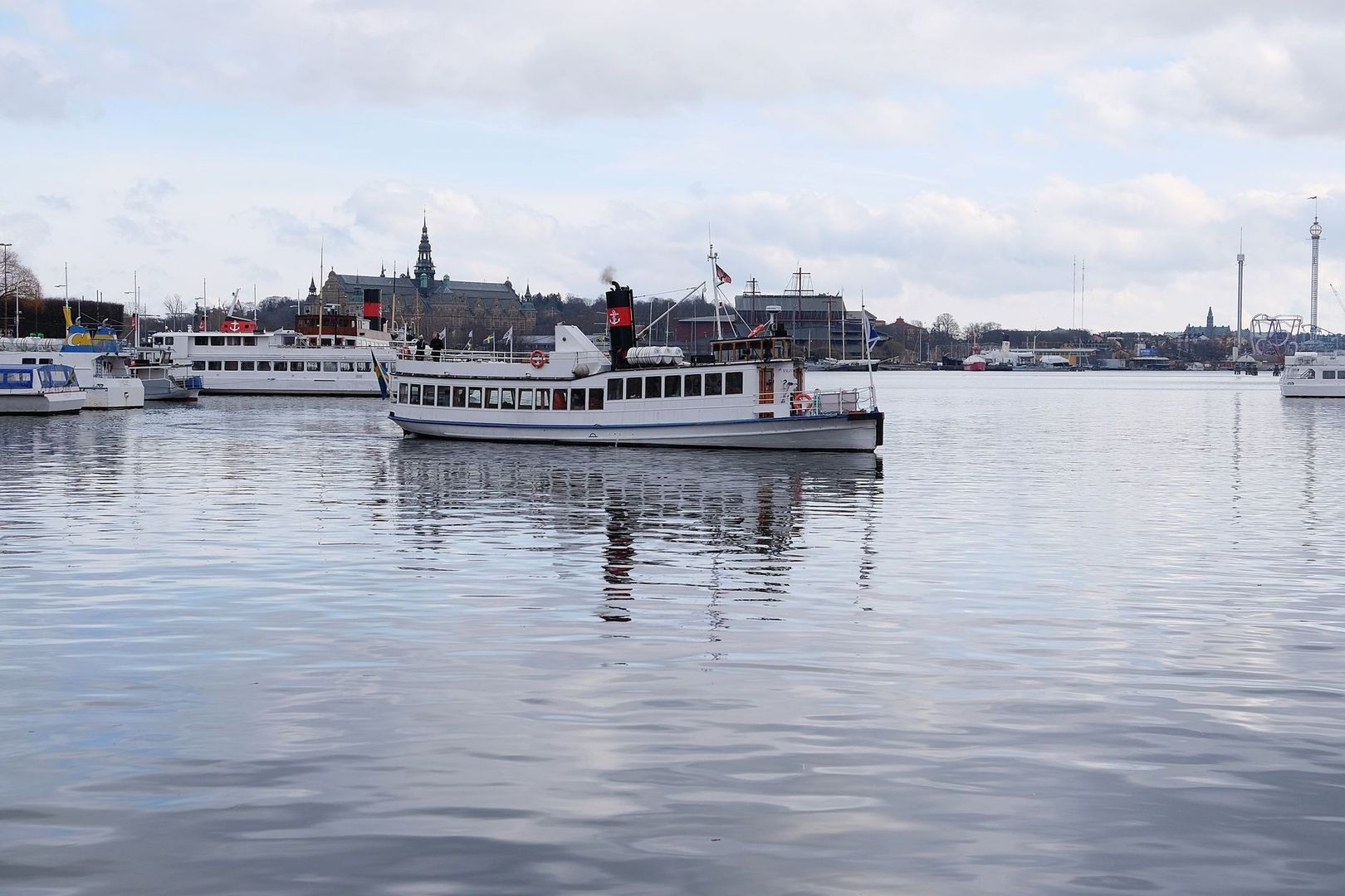 Pendelbåt på Stockholms vatten framför stadens kaj och byggnader